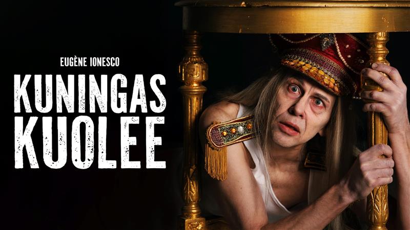 Vanha mies koristeellisessa koppalakissa makaa kultaisen pöydän alla piilossa. Miehen katsoo suoraan kameraan pelokkaasti ja pitelee käsillään kiinni pöydän jalasta. Ympäröivä tausta on musta. Vasemmalla valkoinen teksti "Kuningas kuolee".